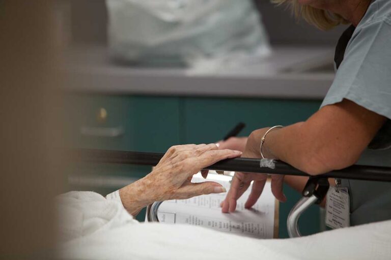 Older adult reviewing medications with a family member at a kitchen table
