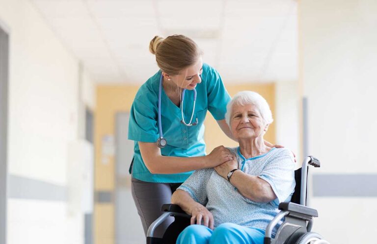 An older adult looking thoughtfully at family photos while a loved one offers gentle support nearby.